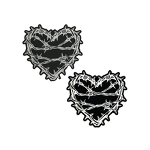 Load image into Gallery viewer, The Barbed Wire Heart Pasties Reflective Nipple Covers by Pastease®. Two black hearts with silver reflective barbed wire patterned shaped nipple covers shown on a white background. Perfect for festivals, pride, burlesque, raves, only fans content or parties.