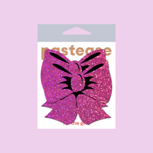 Load image into Gallery viewer, Glittering Hot Pink Bow Nipple Pasties by Pastease®. Two bright pink sparkly big bow shaped nipple covers shown in the pastease packaging on a pastel pink background.