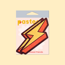 Load image into Gallery viewer, The Lightning Bolt Pasties Thunder Struck Breast Covers by Pastease®. Two glitter velvet orange and yellow zig zag lightning bolt nipple covers shown in the pastease pastel packaging on a pastel yellow background. Perfect for a festival, burlesque performance, pride or parties.