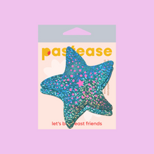 Load image into Gallery viewer, The Starfish: Twinkling Seafoam Green & Pink Print Sea Star Nipple Pasties by Pastease®. Two aqua blue with holographic glitter and pink dots starfish shaped nipple covers shown in the pastease pastel packaging on a light purple background. Perfect for a festival, burlesque performance, pride or parties.