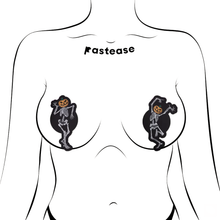 Load image into Gallery viewer, Dancing Skeletons Pasties with Pumpkin Heads Spooky Scary Skeletons nipple covers shown on an outline of feminine chest. One of the skeletons is dancing with one leg in the air and both arms up, while the other is dancing with arms bent and legs together. Both skeletons have orange spooky faced pumpkin heads.