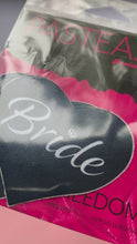 Load and play video in Gallery viewer, Video of the Love: Black 'Bride' Heart Nipple Pasties by Pastease in the pink and black pastease packaging.