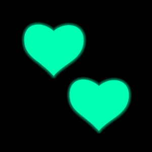 Glowing Pastease® Neon Turquoise Heart Pasties on a black background. The illuminated hearts stand out boldly, capturing the fun, flirty spirit of this small family-run brand that creates nipple covers for all breast shapes and sizes.