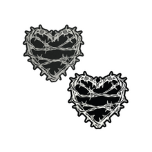 Load image into Gallery viewer, The Barbed Wire Heart Pasties Reflective Nipple Covers by Pastease®. Two black hearts with silver reflective barbed wire patterned shaped nipple covers shown on a white background. Perfect for festivals, pride, burlesque, raves, only fans content or parties.
