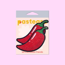 Load image into Gallery viewer, Chilli Pepper Pasties in Spicy Red by Pastease. Two sparkly glitter red chilli pepper shaped nipple covers shown in the pastease packaging on a pink background.

