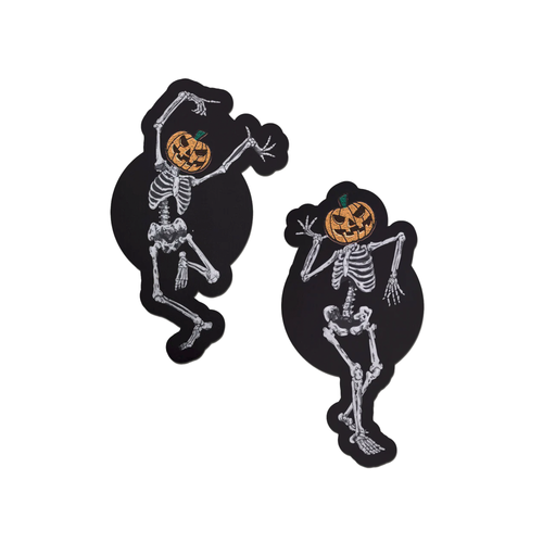 Dancing Skeletons Pasties with Pumpkin Heads Spooky Scary Skeletons nipple covers on a white background. One of the skeletons is dancing with one leg in the air and both arms up, while the other is dancing with arms bent and legs together. Both skeletons have orange spooky faced pumpkin heads.