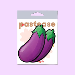 The Eggplant Pasties Fat Purple Emoji Nipple Covers by Pastease in the pastease cellophane packaging on a pastel purple background. Two large purple eggplant aubergine vegetable emoji style nipple covers with green leaves at the top. Perfect for a festival, burlesque performance, drag shows, pride or parties.