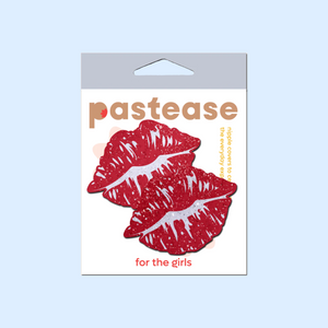 Kisses: Sparkly Red Kissing Puckered Lips Nipple Covers by Pastease. Two glitter red kissing lip shaped nipple covers shown in the pastease packaging on a pastel blue background.