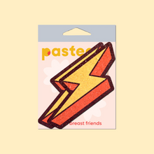 Load image into Gallery viewer, The Lightning Bolt Pasties Thunder Struck Breast Covers by Pastease®. Two glitter velvet orange and yellow zig zag lightning bolt nipple covers shown in the pastease pastel packaging on a pastel yellow background. Perfect for a festival, burlesque performance, pride or parties.
