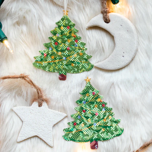 Christmas Tree Nipple Pasties by Pastease®. Two green glittery Christmas tree shaped nipple covers, shown on white fur background with star and moon Christmas decorations. Perfect for a festival, burlesque performance, pride, Christmas or parties