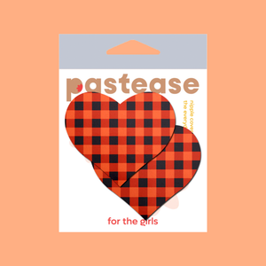 Love: Gingham Orange & Black Halloween Plaid Nipple Pasties by Pastease®. Two red and black gingham heart shaped nipple covers in packet, shown on orange background. Perfect for festivals, pride, burlesque, raves, only fans content or parties.