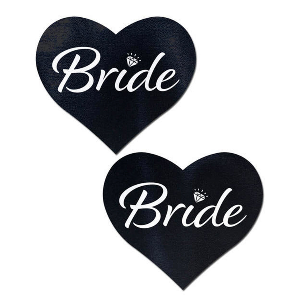 Love: Black 'Bride' Heart Nipple Pasties by Pastease. Two black heart shaped nipple covers with Bride written in white script text with a small diamond over the i, shown on a white background. Perfect for a festival, pride, burlesque performance, only fans content or a party.