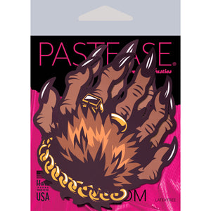 Monster Hands Pasties: Classy Werewolf Claws Nipple Covers by Pastease®. Two brown monster hands with long claws and gold jewellery in a clasped shape nipple covers in pink and black cellophane packaging.