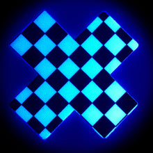Load image into Gallery viewer, The Plus X: Black &amp; White Checker Cross Nipple Pasties by Pastease shown glowing in the dark with a blue hue on a black background.
