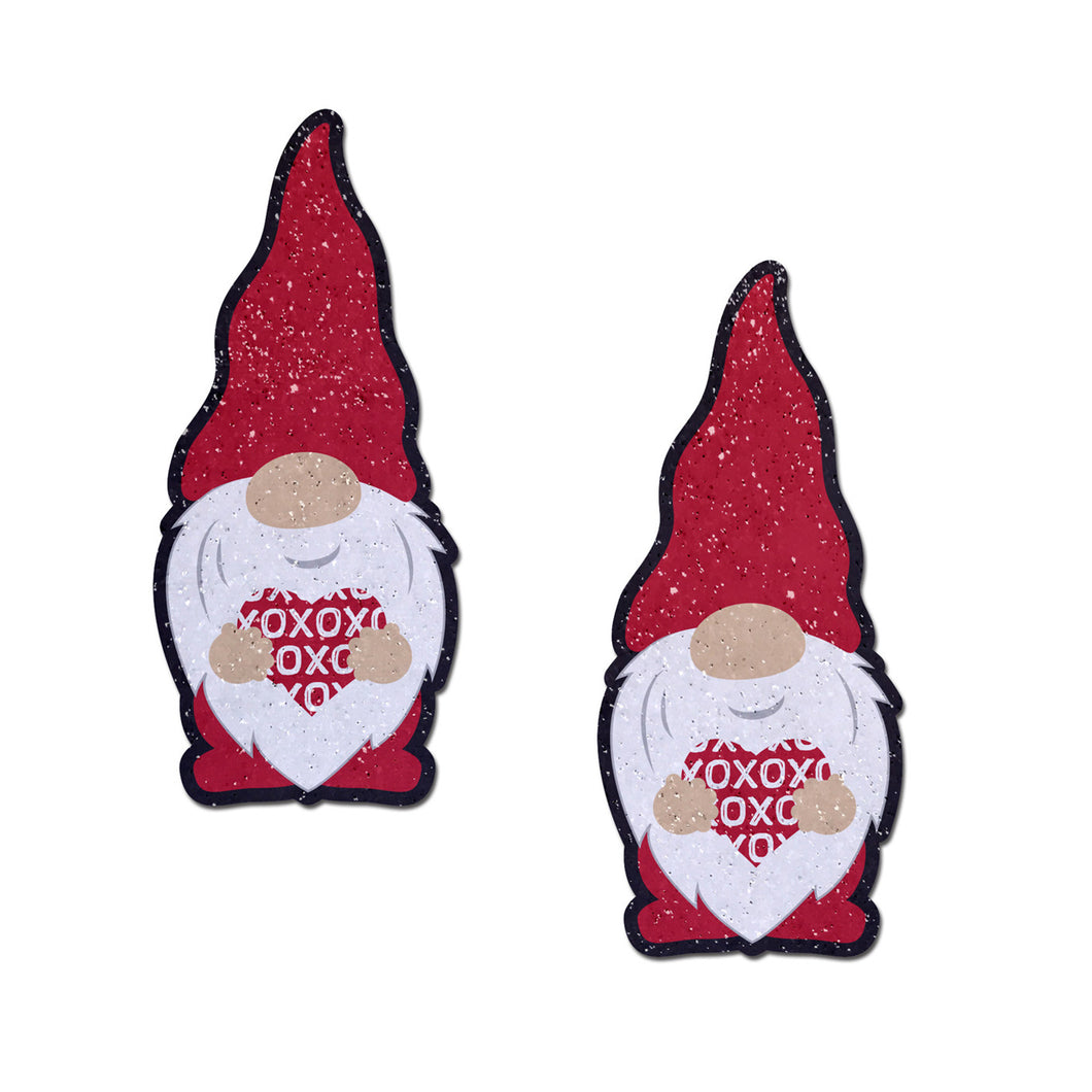 Valentine Sweetheart Garden Gnome Gonk Nipple Covers by Pastease®. Two red glitter gonk gnomes smiling holding up a red heart with repeating white XOXO pasties shown on a white background. Perfect for a festival, pride, burlesque performance, only fans content or a party.